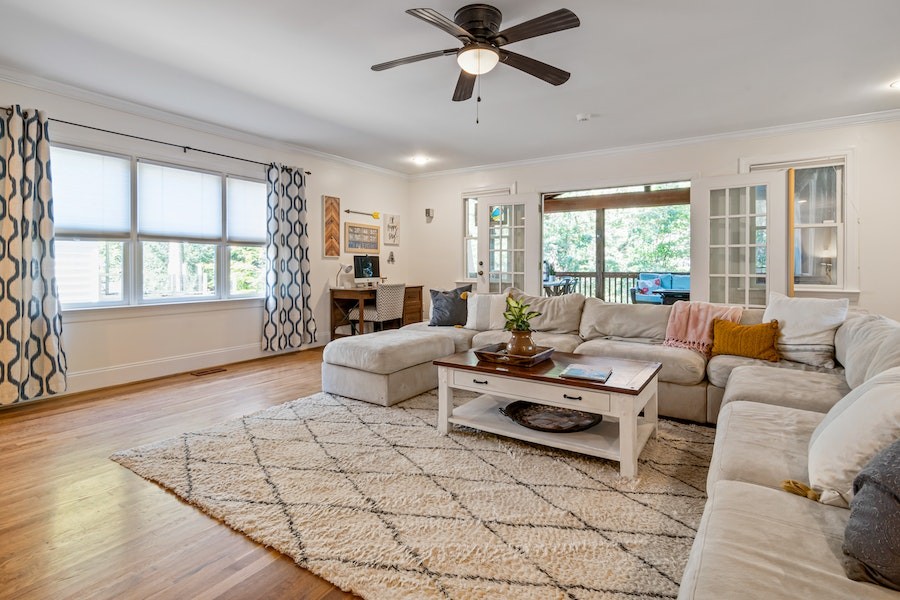 Photo of a beautiful, spacious living room with a ceiling fan hanging over the center. 