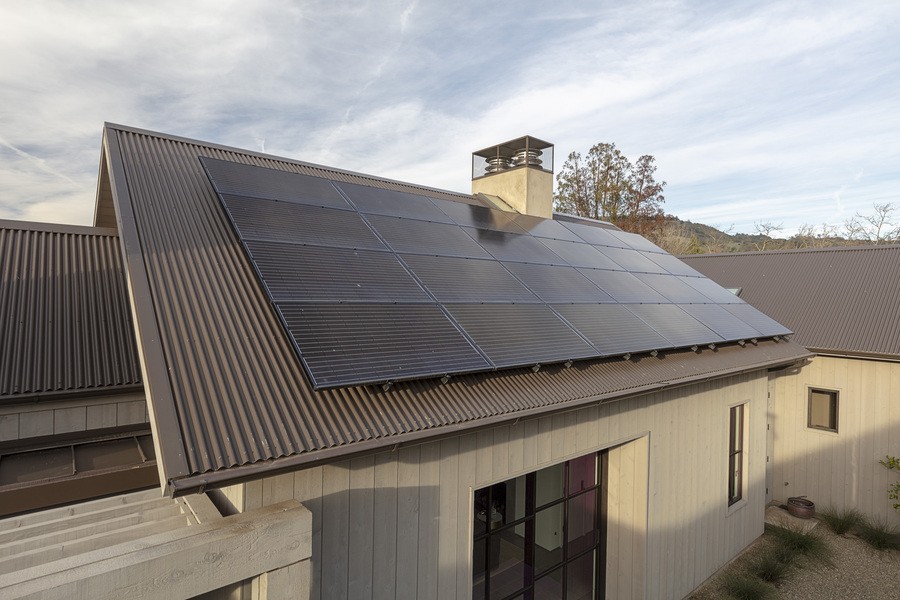 Solar panels installed on a modern home’s metal roof, capturing renewable energy under clear skies.