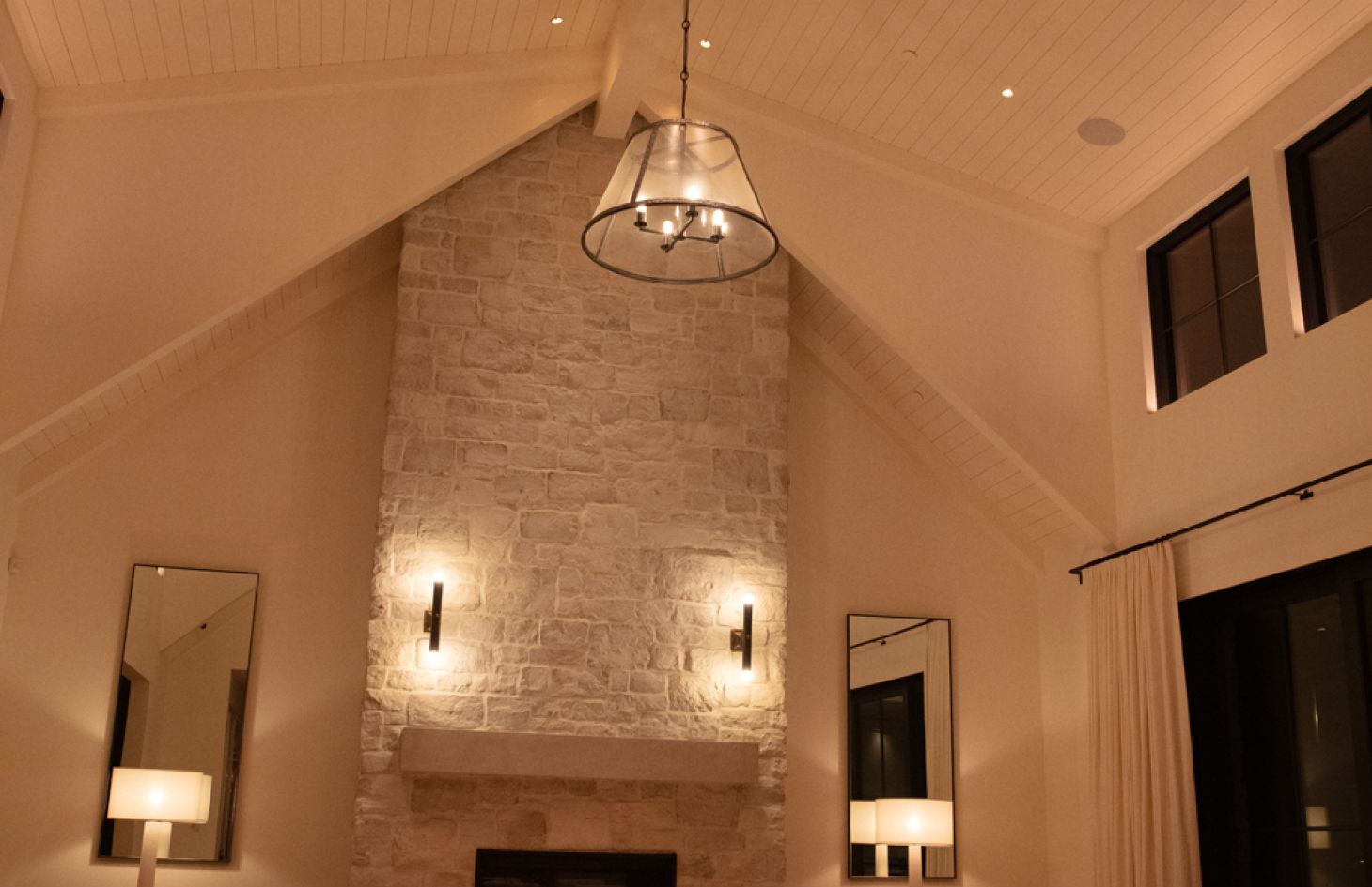 A chic dining area featuring a long, sleek table with modern chairs, complemented by a striking pendant light overhead and tasteful decorative accents on the walls.